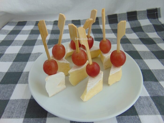 bordje met stukjes brie met een rode druif