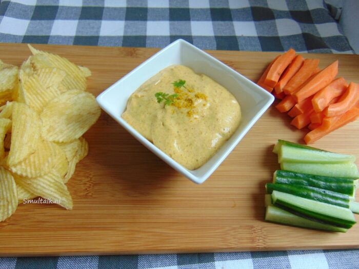 kerrie dipsaus met chips en rauwkost op houten plank